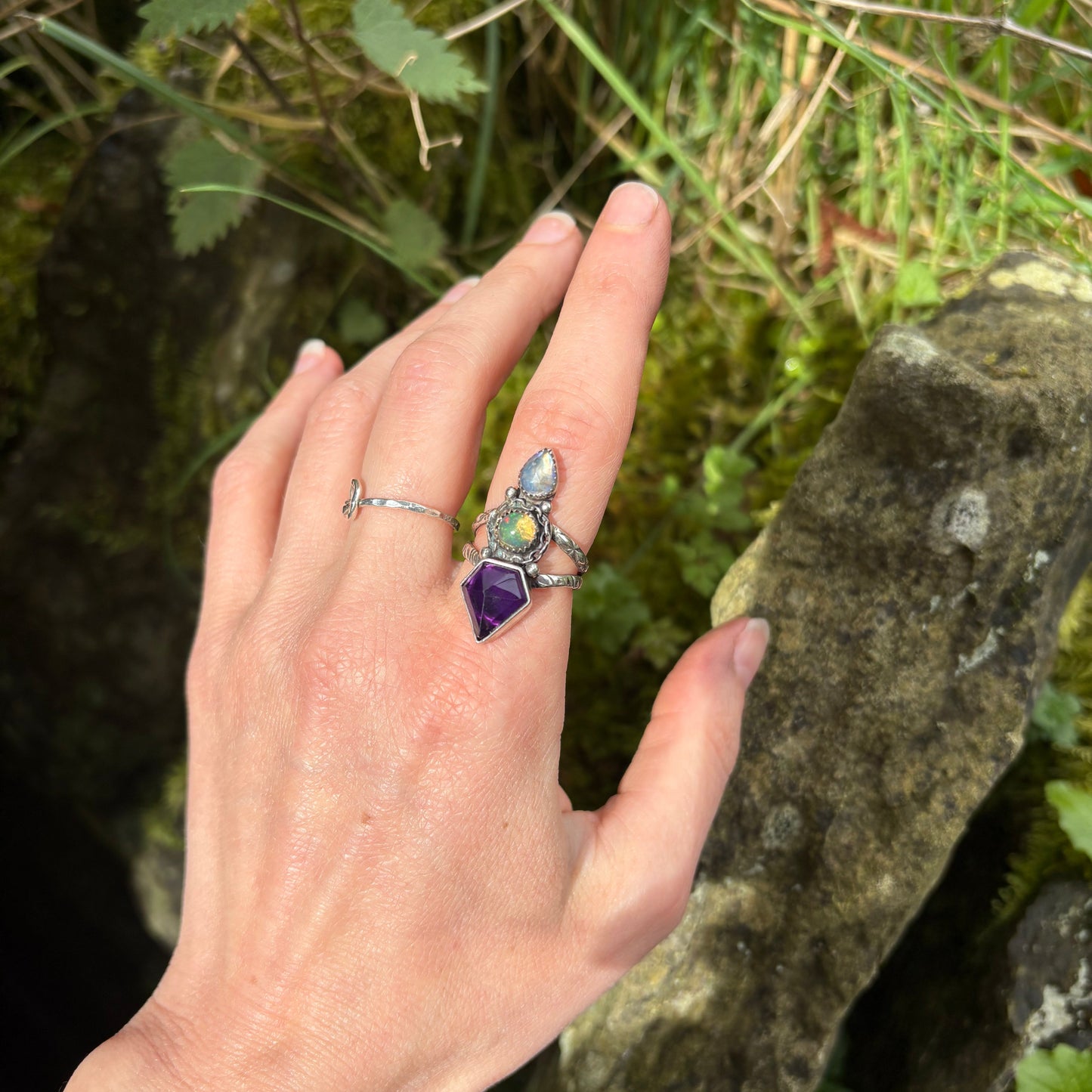 hand wearing artisan ring of amethyst, opal and moonstone