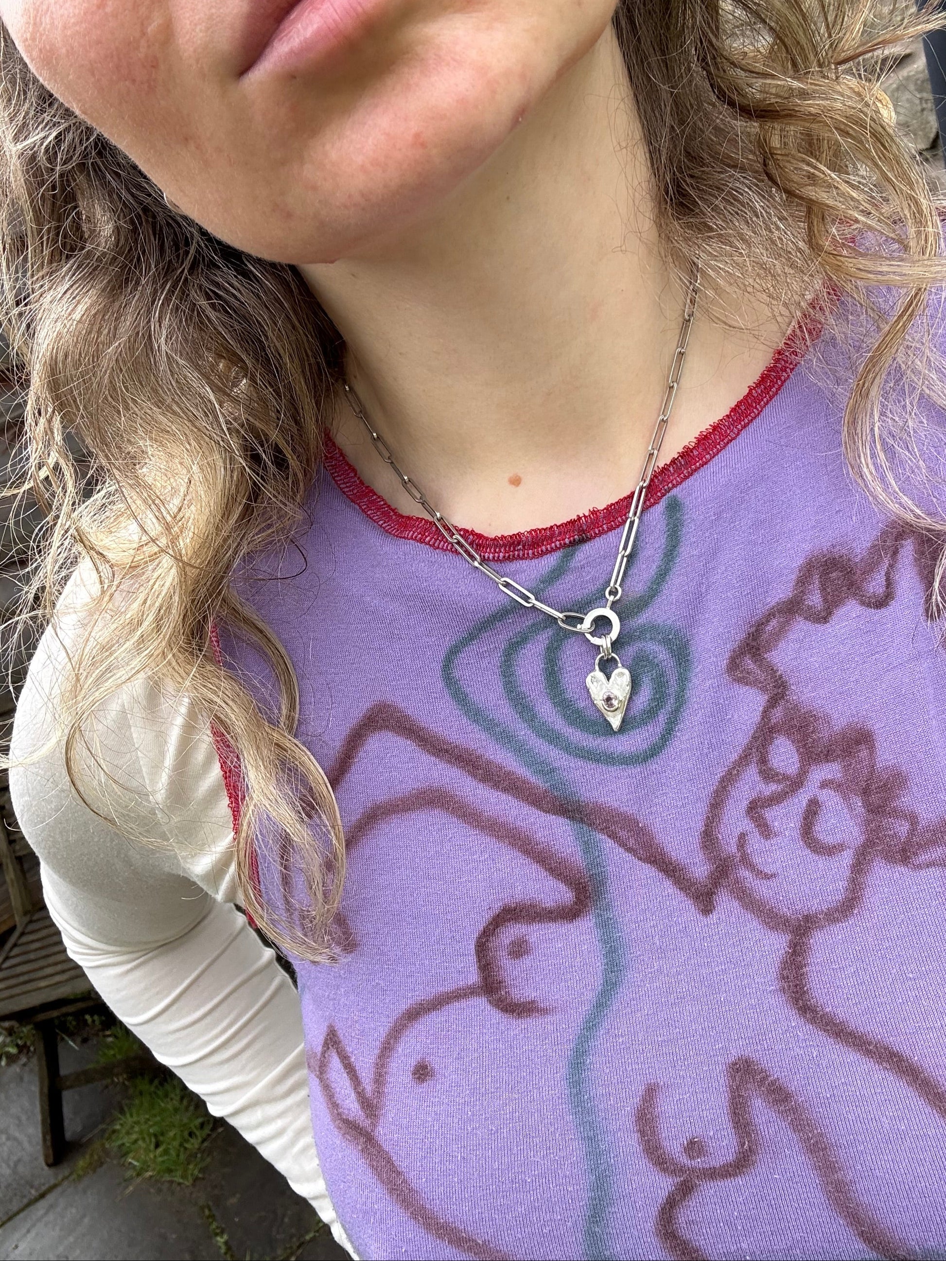 Person wearing a silver and pink tourmaline necklace with a ring clasp 