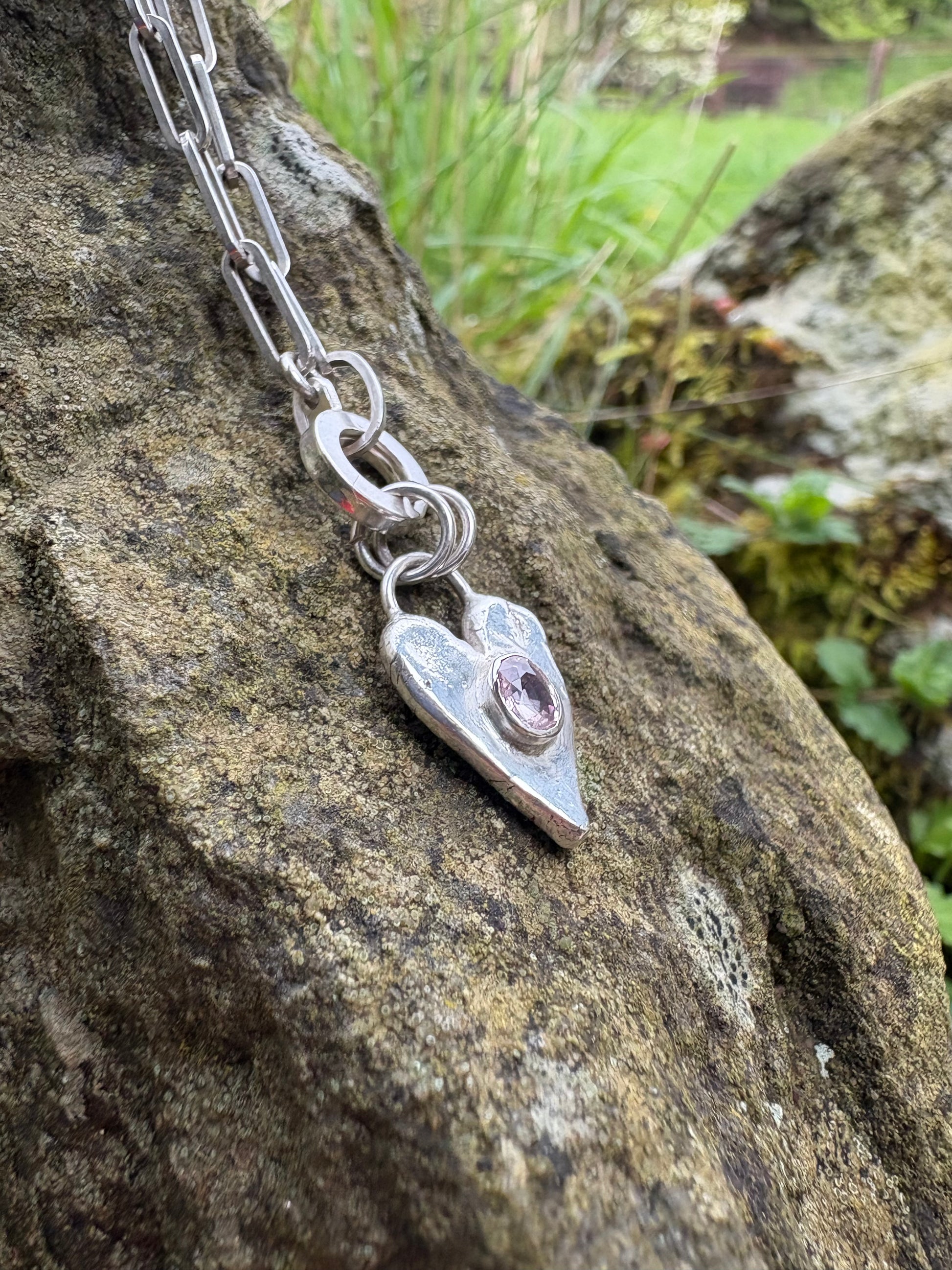 Silver chain with a heart-shaped clasp on a rock