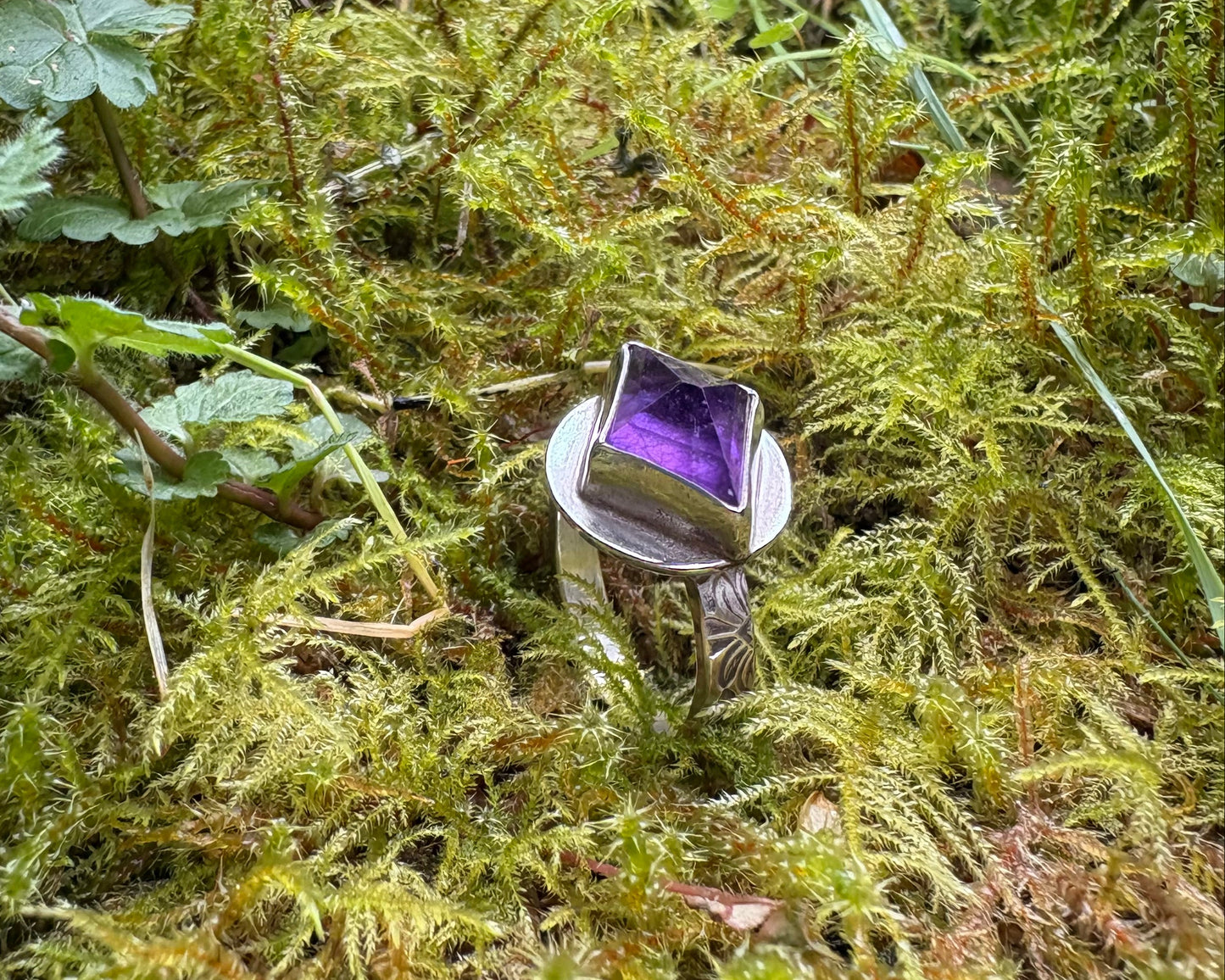 amethyst ring with decorative band on a bed of moss 