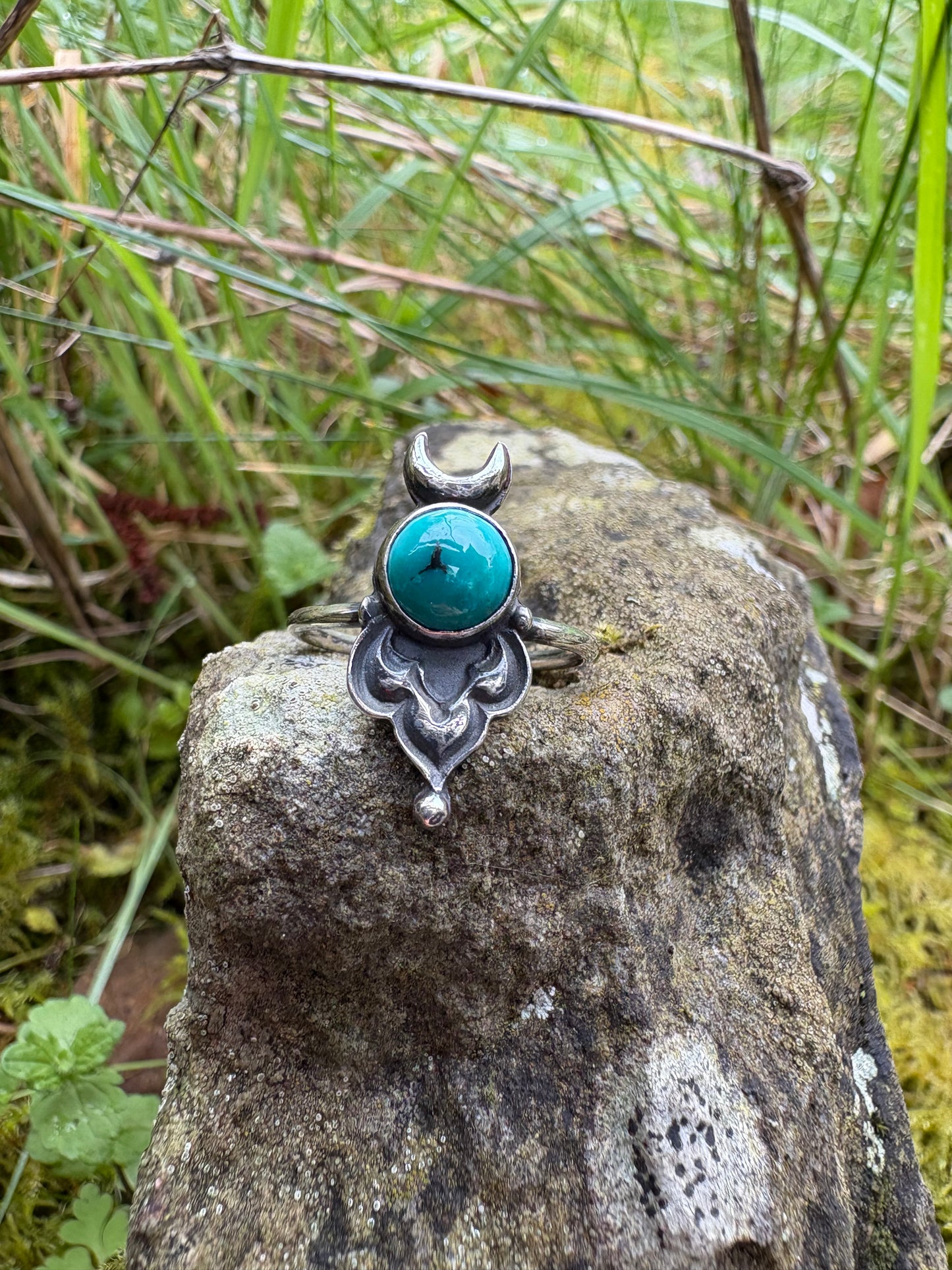Silver ring with a turquoise stone on a rock in a natural setting